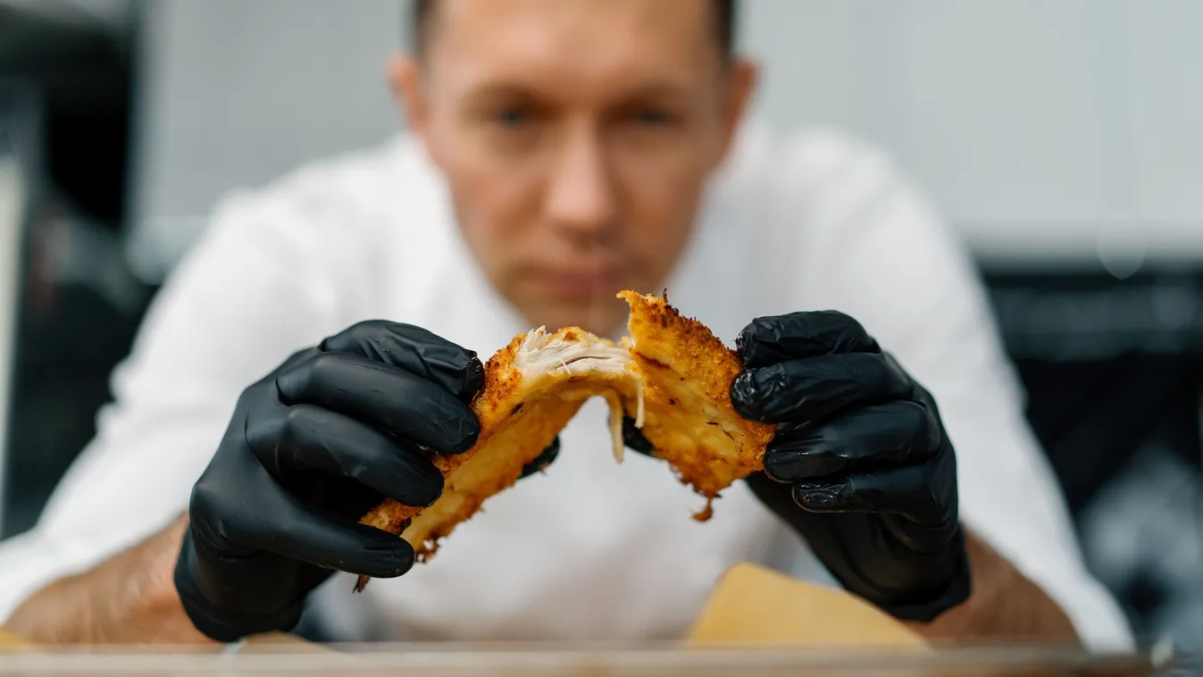 Tökéletes panírban lévő húst kettétörő séf fekete kesztyűben