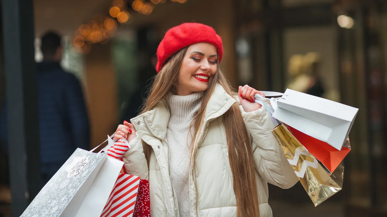 Karácsonyi leárazások után vásárló boldog nő, szatyrokkal a kezében.