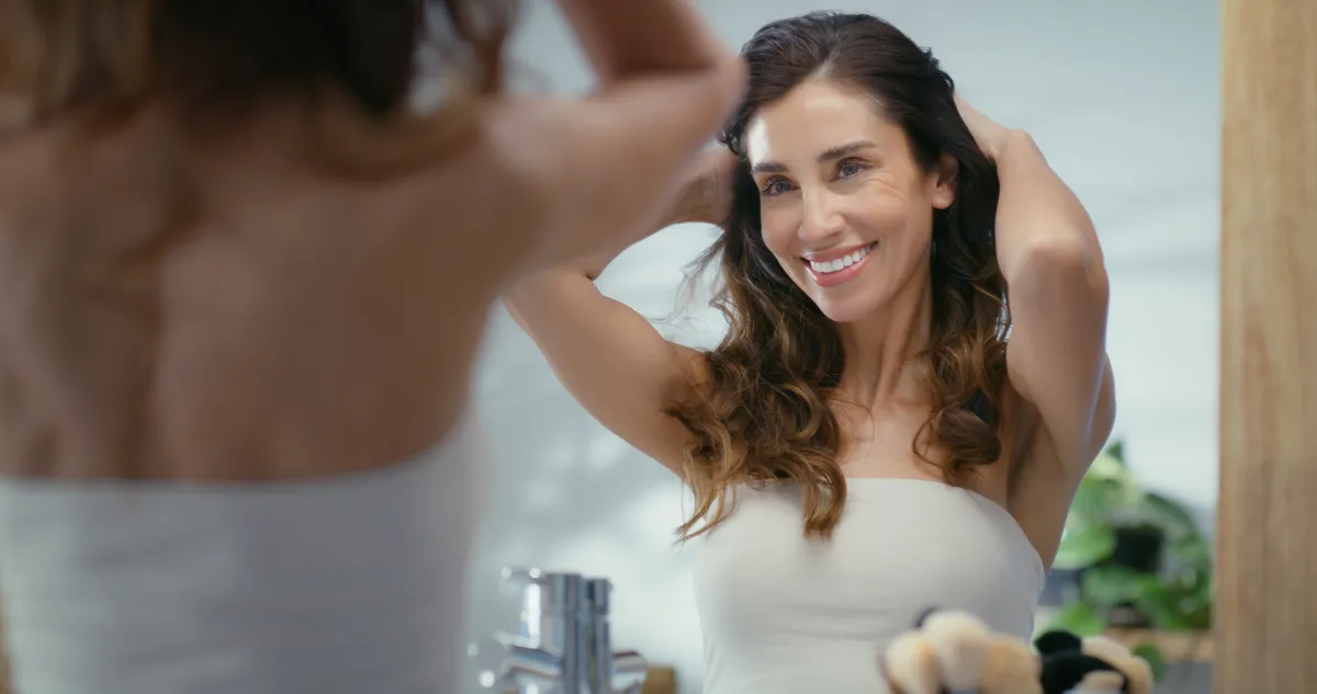 Középkorú nő néz magát a tükörben, aki küzd a ráncok ellen.