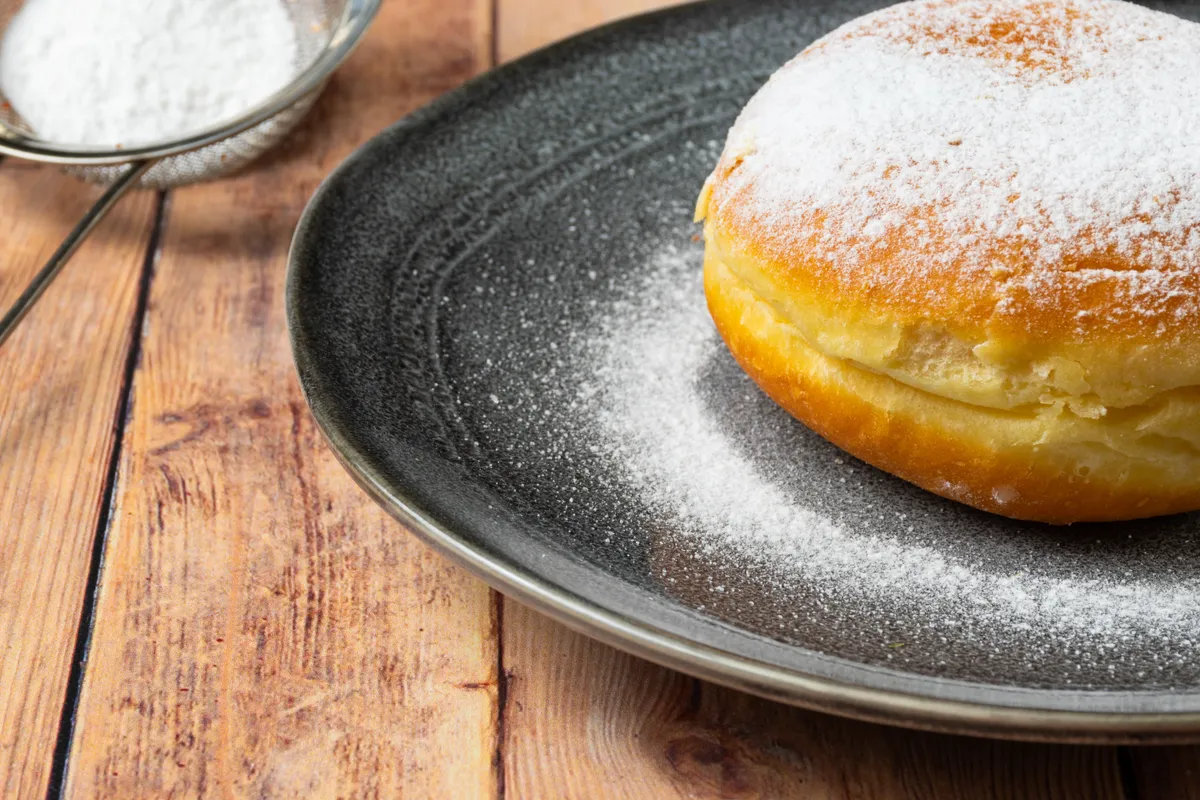 Farsangi fánk története: szalagos fánk egy tálon, porcukorral meghintve