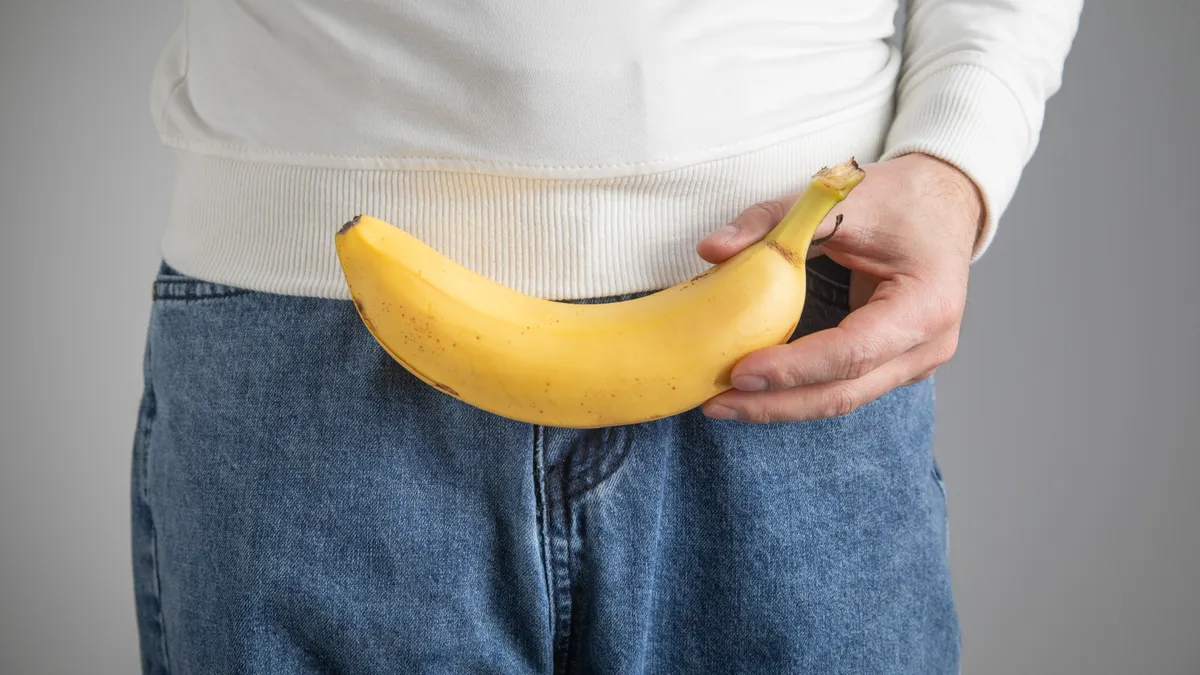 Péniszméretet szimbolizáló banán slicc elé tartása
