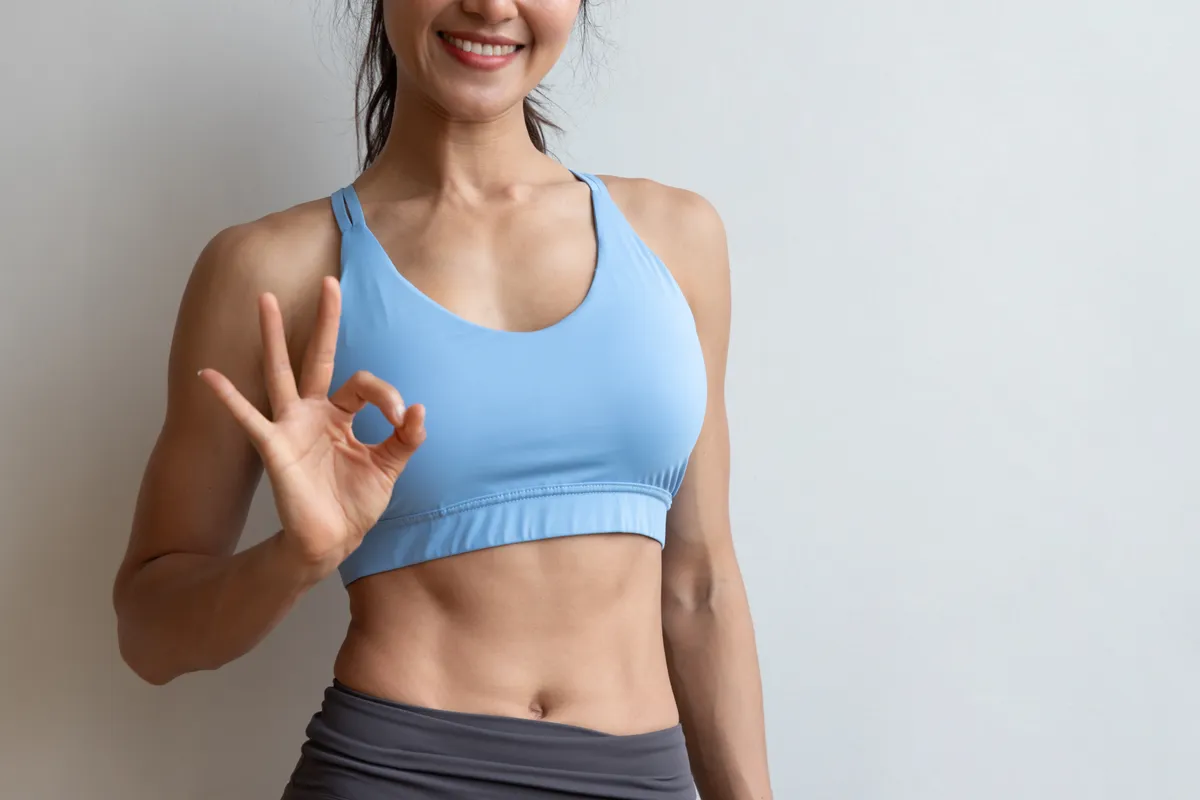 Mosolygó coregazmust átélő nő edzős ruhában.