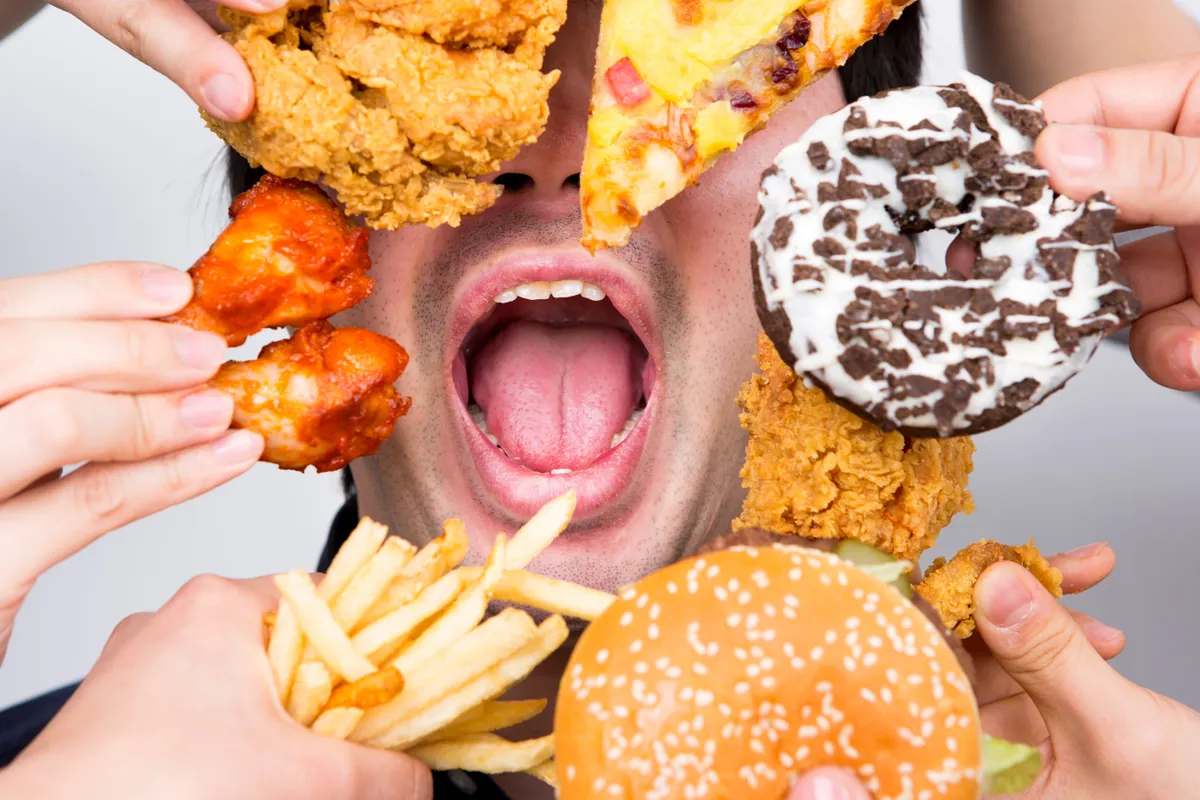 Böjt előtti lakomázás - egy férfi hamburgert és sült krumplit fogyaszt.