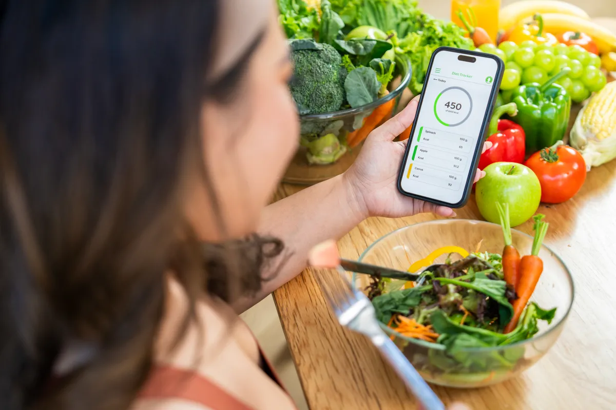 Egy nő salátát eszik és kalóriát számol a diéta alatt.