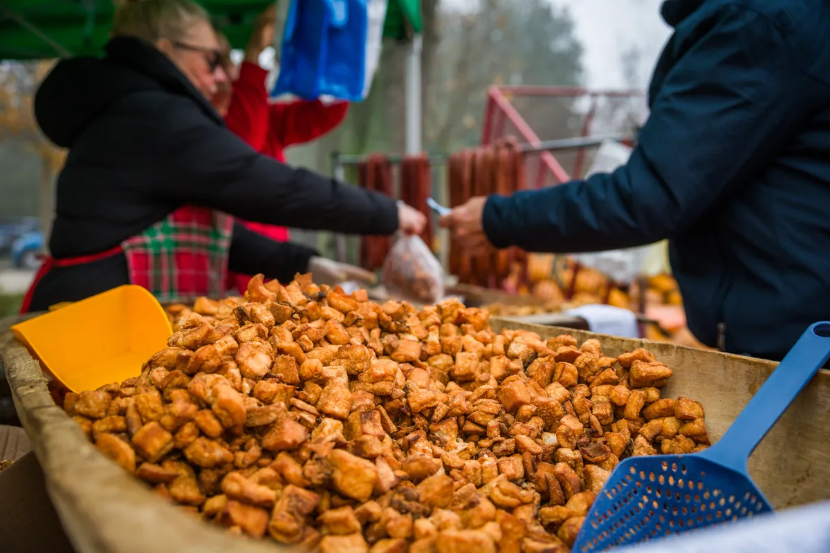 Hétvégi programajánlóban szereplő kép egy nagy teknő tepertőről a háttérben egyéb disznóságokkal, árusokkal és vásárlókkal