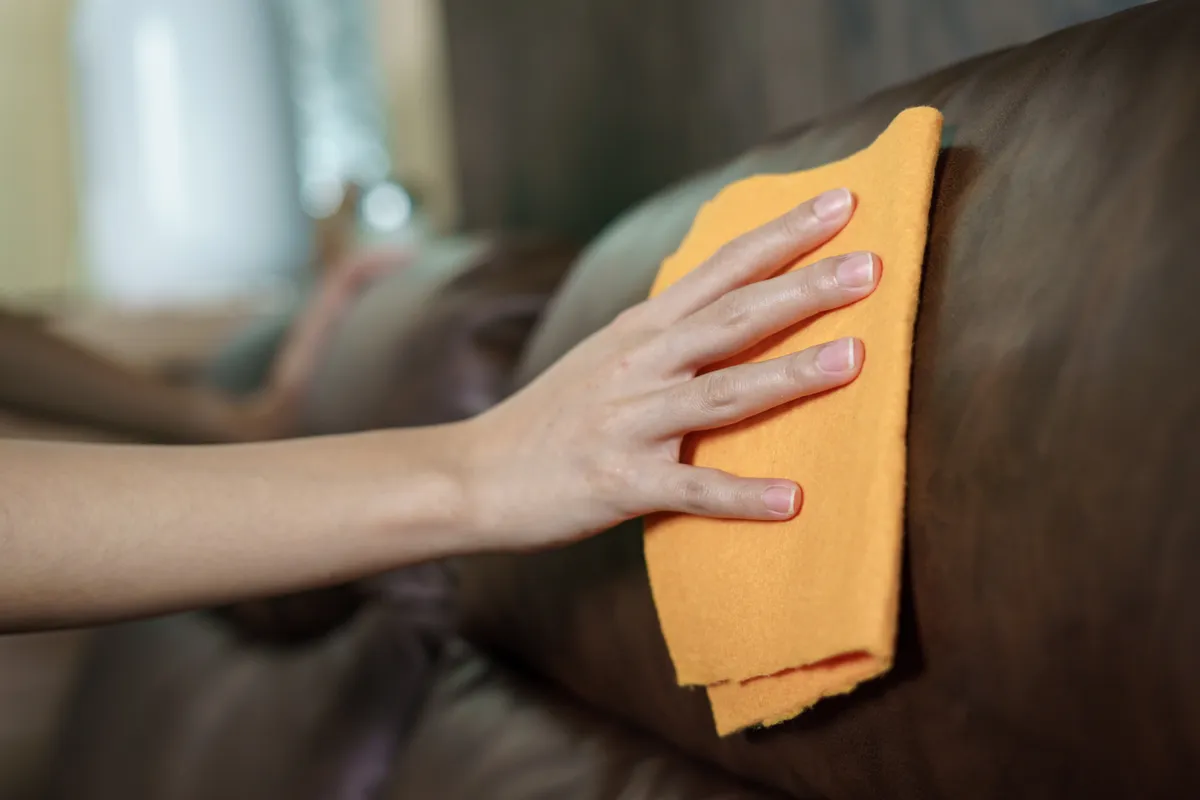 Egy nő a bőrkanapé tisztítását végzi.