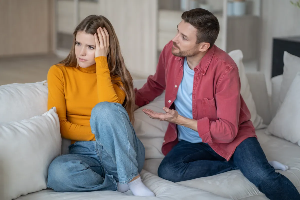 Bizalom teszt: Bizalmi problémákkal küzdő nő ül a kanapén a párjával.