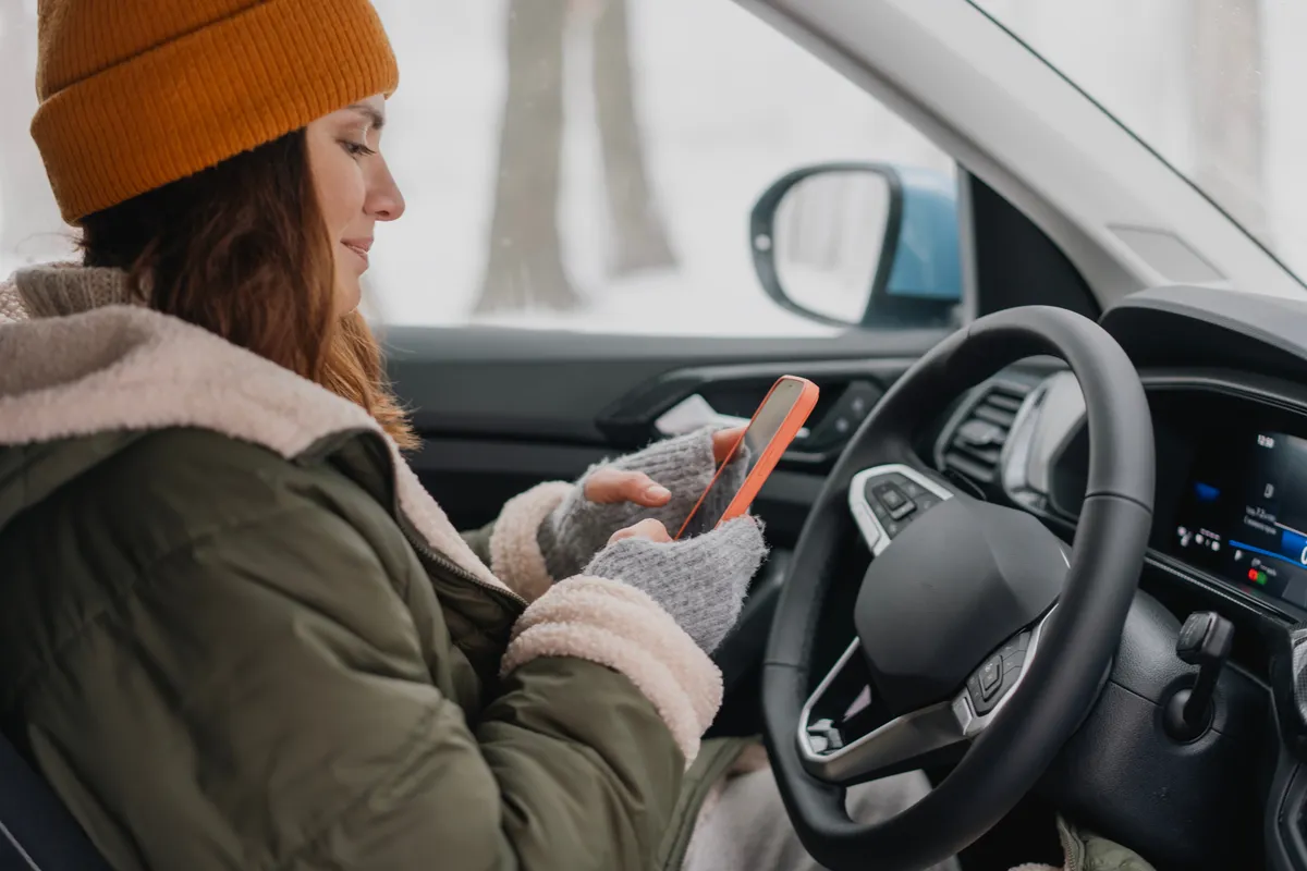 Nő telefonozik télen az autóban.