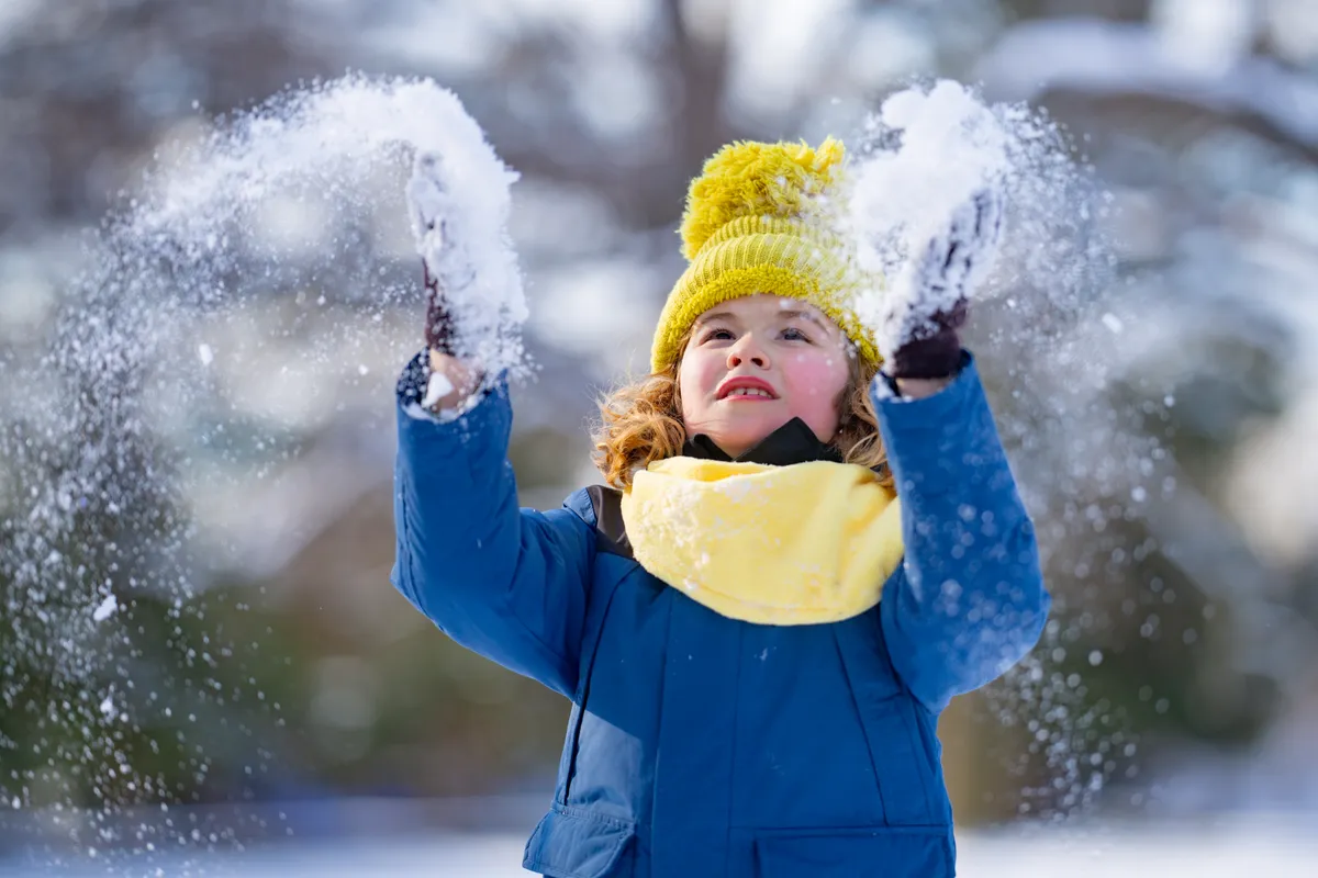 Téli program gyerekeknek: egy kislány éppen játszik a hóban.