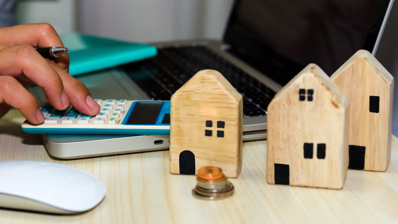 Otthontámogatást illusztráló kisház makettek,. számológép és laptop
