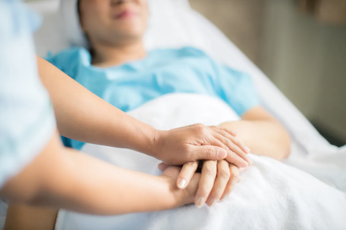 Fekvőbeteg fogja egy szerette kezét a halál előtti percekben.