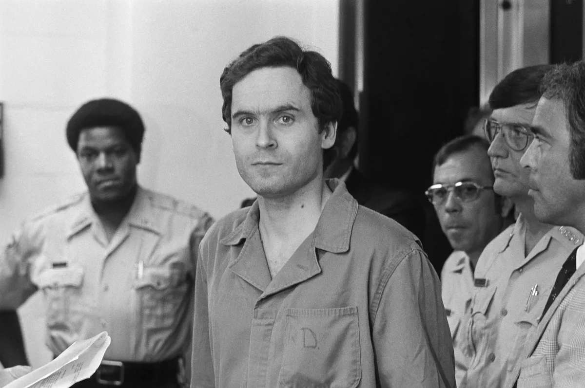 Ted Bundy sorozatgyilkos a tárgyalásán rendőrökkel körülvéve. 