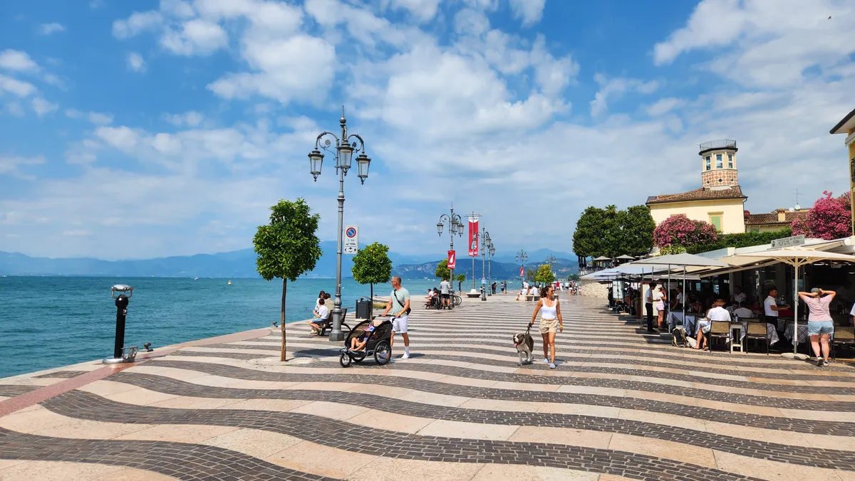 Sétány a Garda-tó partján sétáló emberekkel.