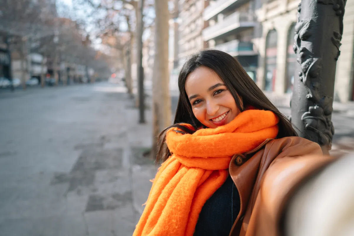 Színes sálat viselő fiatal nő, divatos téli szettben.