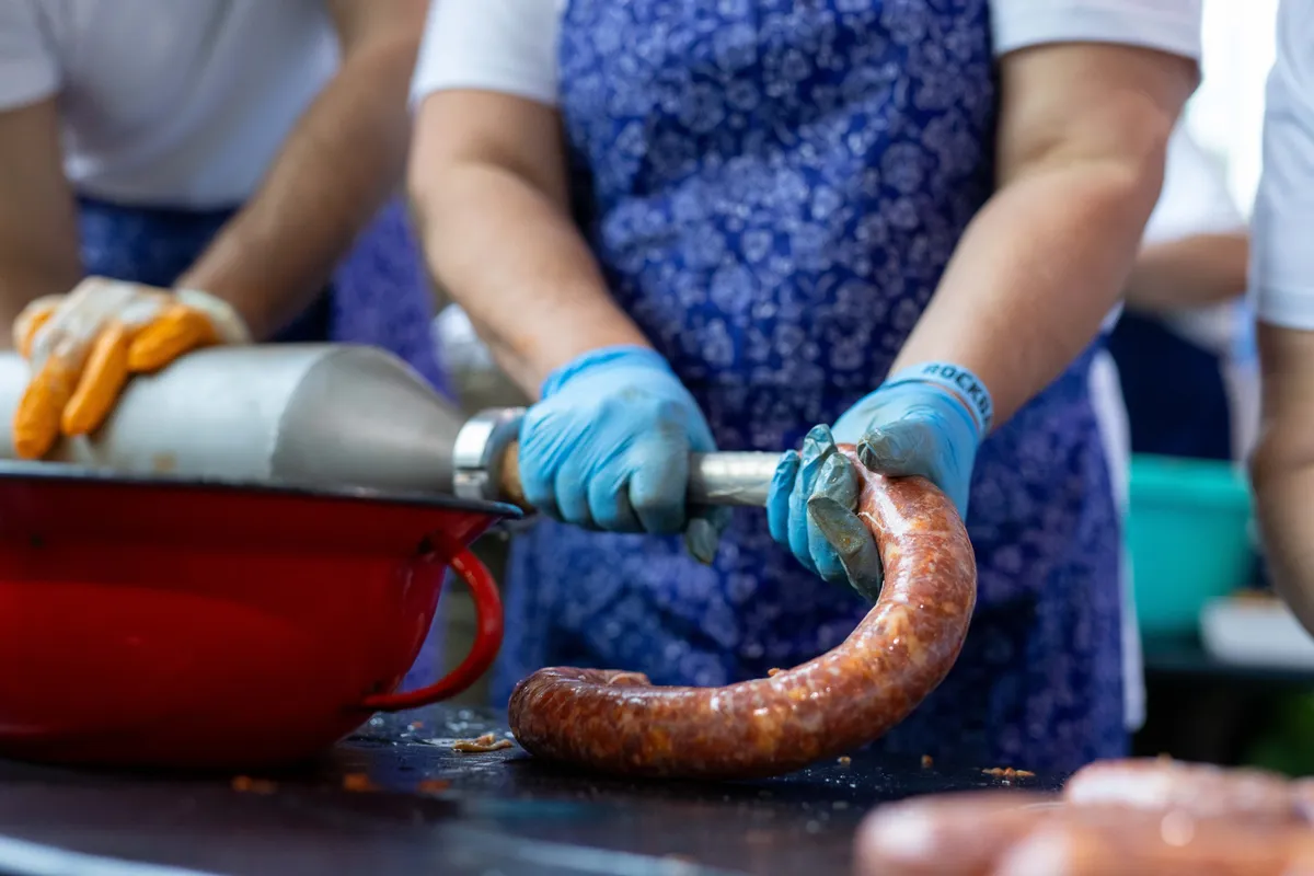 Női kezek, miközben kolbászt töltenek az eseményen.