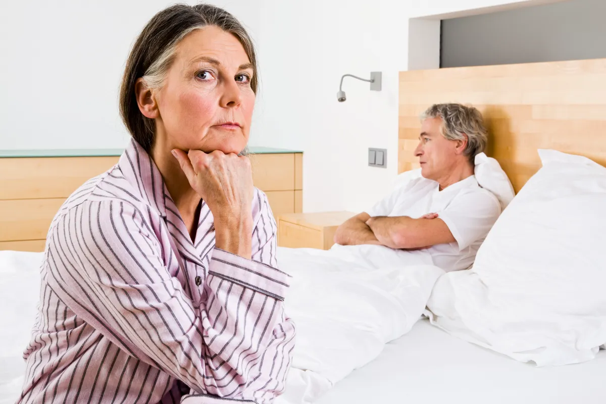 Unott feleség együttlét előtt ül az ágyon a férje mellett.