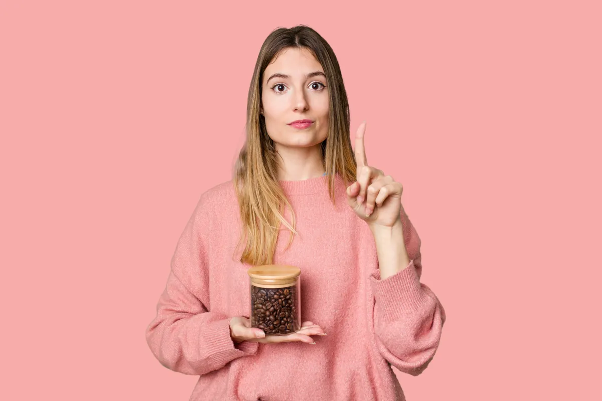 Fiatal nő, kezében egy kávészemekkel teli üveggel