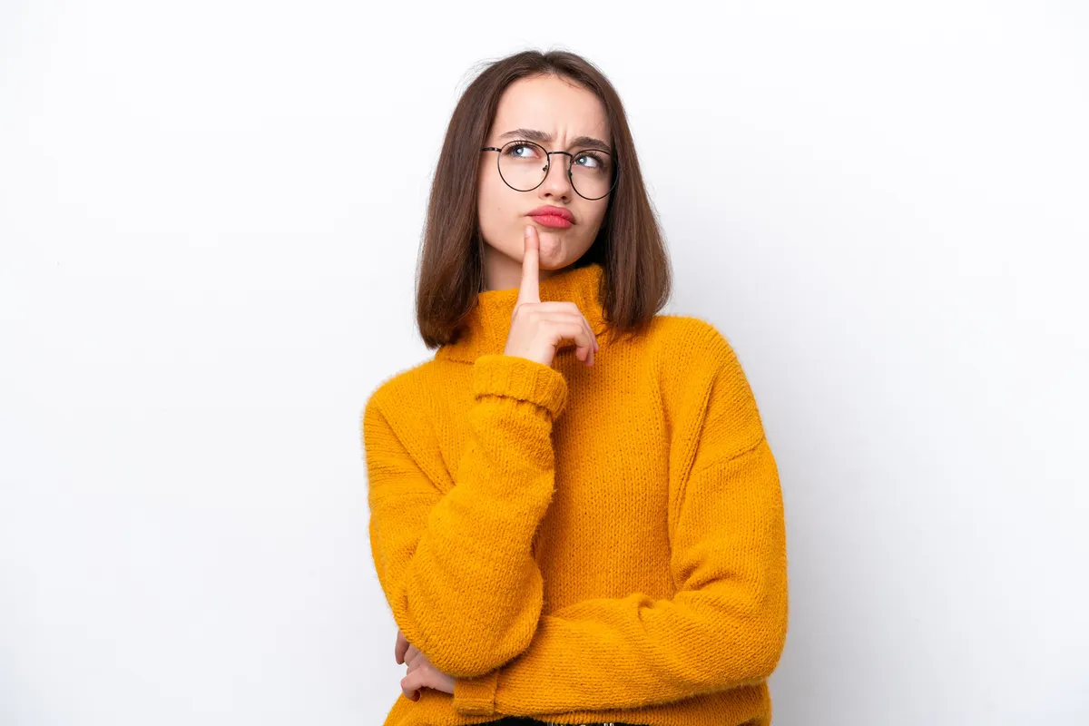 Földrajz kvízen gondolkodó, szemüveges fiatal nő.