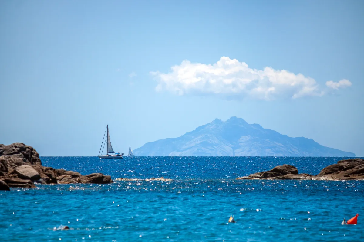 Montecristo szigete tengerrel, előtérben vitorlásokkal és kisebb szigetekkel, sziklákkal. 