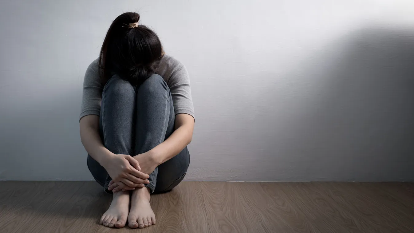 Tanult tehetetlenségben szenvedő depressziós fiatal nő a falnál ülve