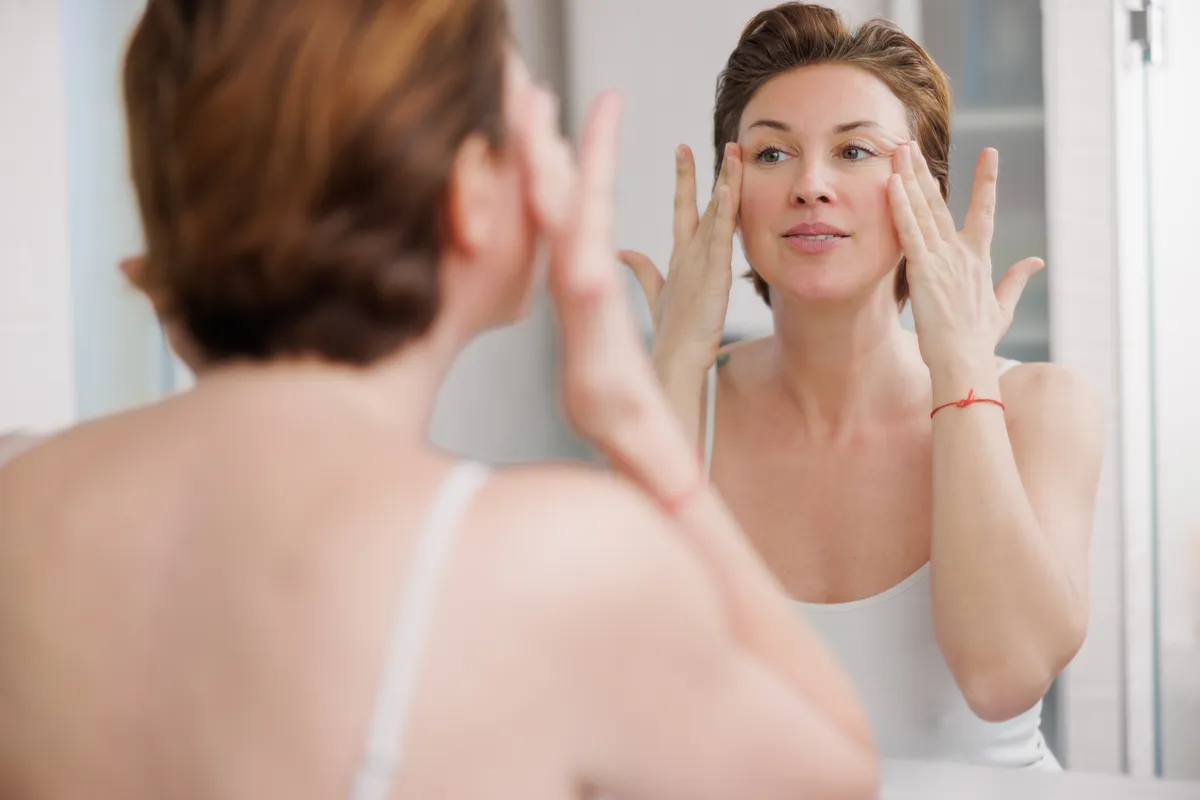 Fiatalos megjelenésű nő otthoni arcmasszázst csinál.