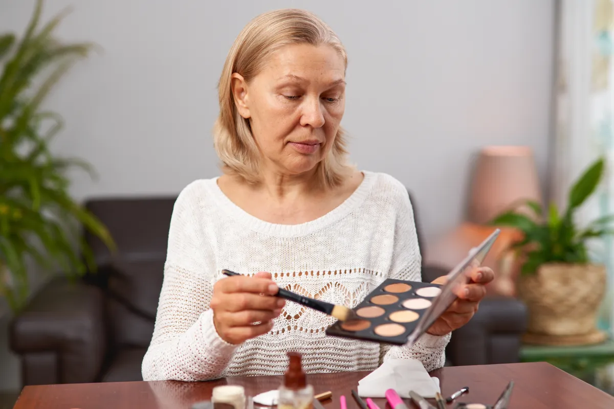 Finoman sminkelő középkorú nő, aki nem vét sminkhibát.