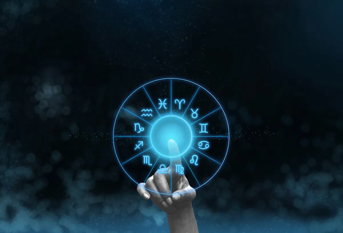 Női kéz egy horoszkópban használt zodiákus kör mögött.