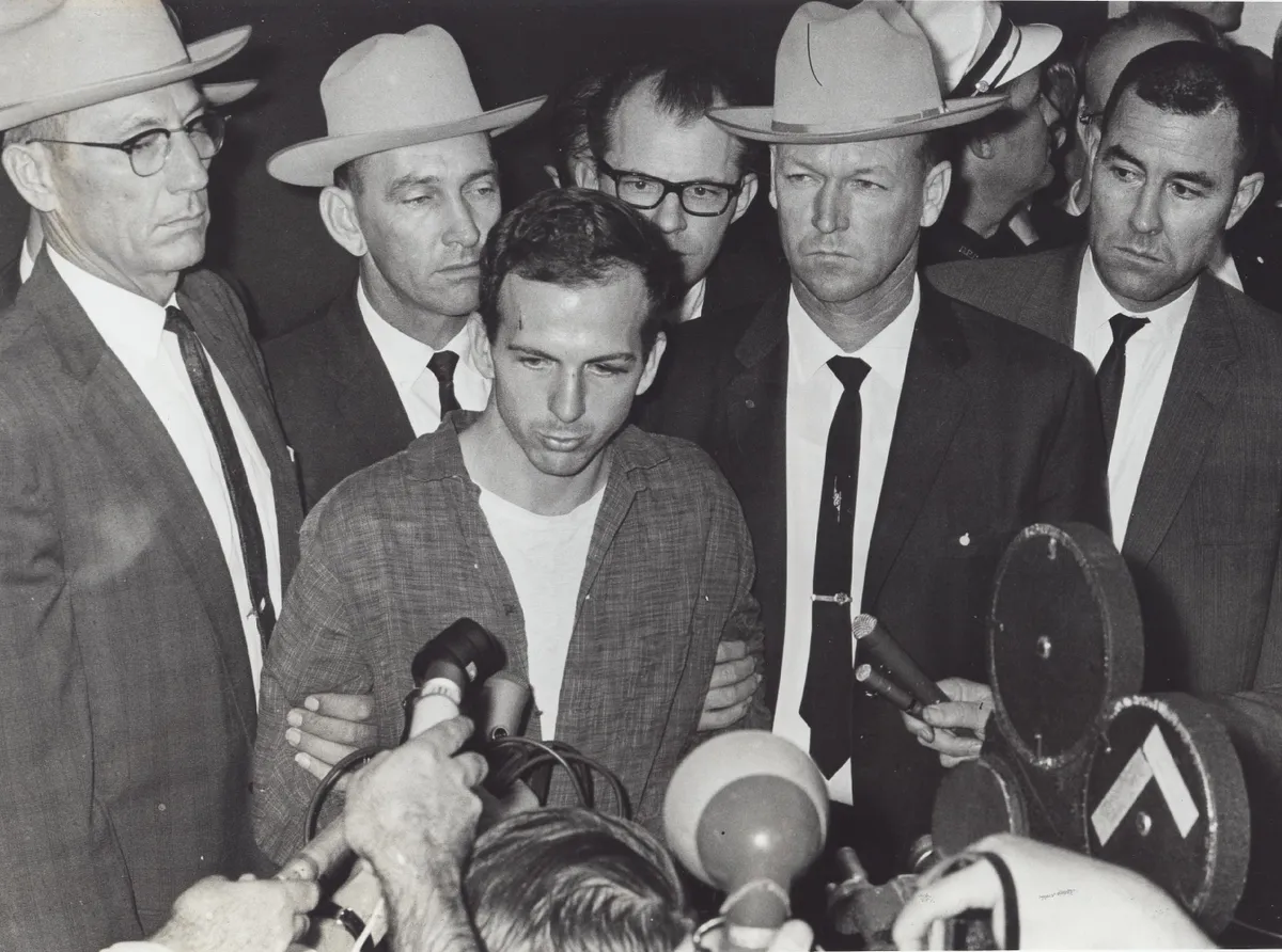 Lee Harvey Oswald, a Kennedy-gyilkosság gyanúsítottja riporterek és rendőrök gyűrűjében. 