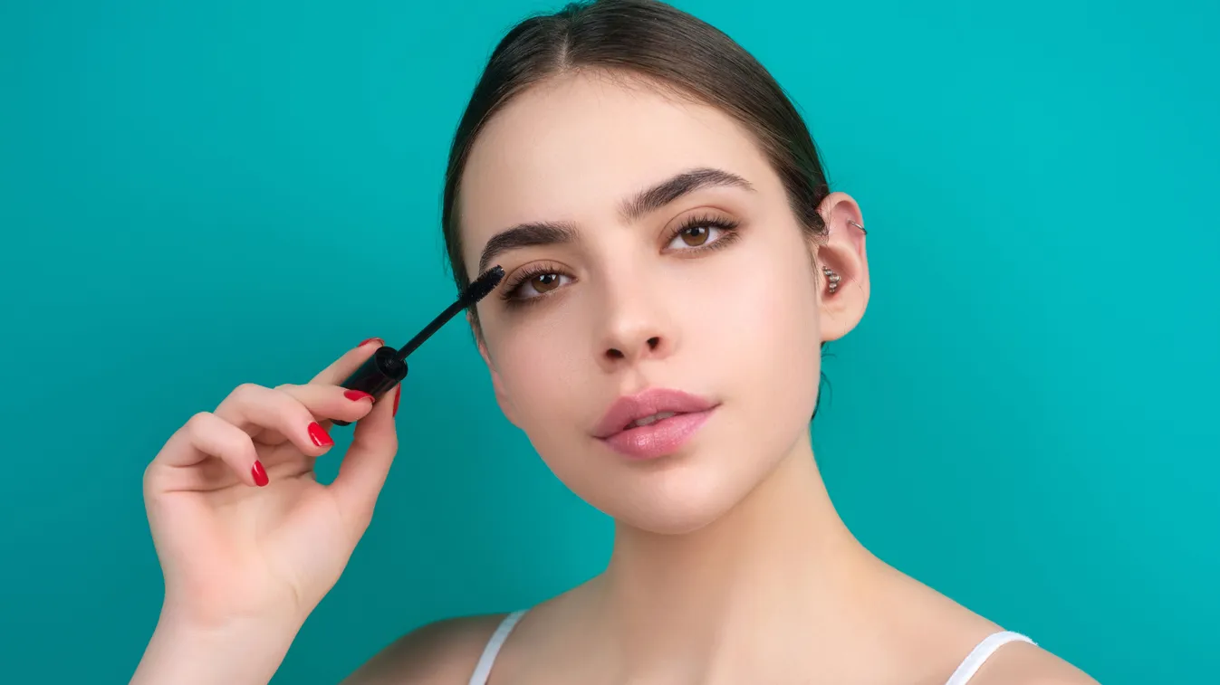 Szempillanövesztő szérumot szempillaspirállal alkalmazó fiatal nő