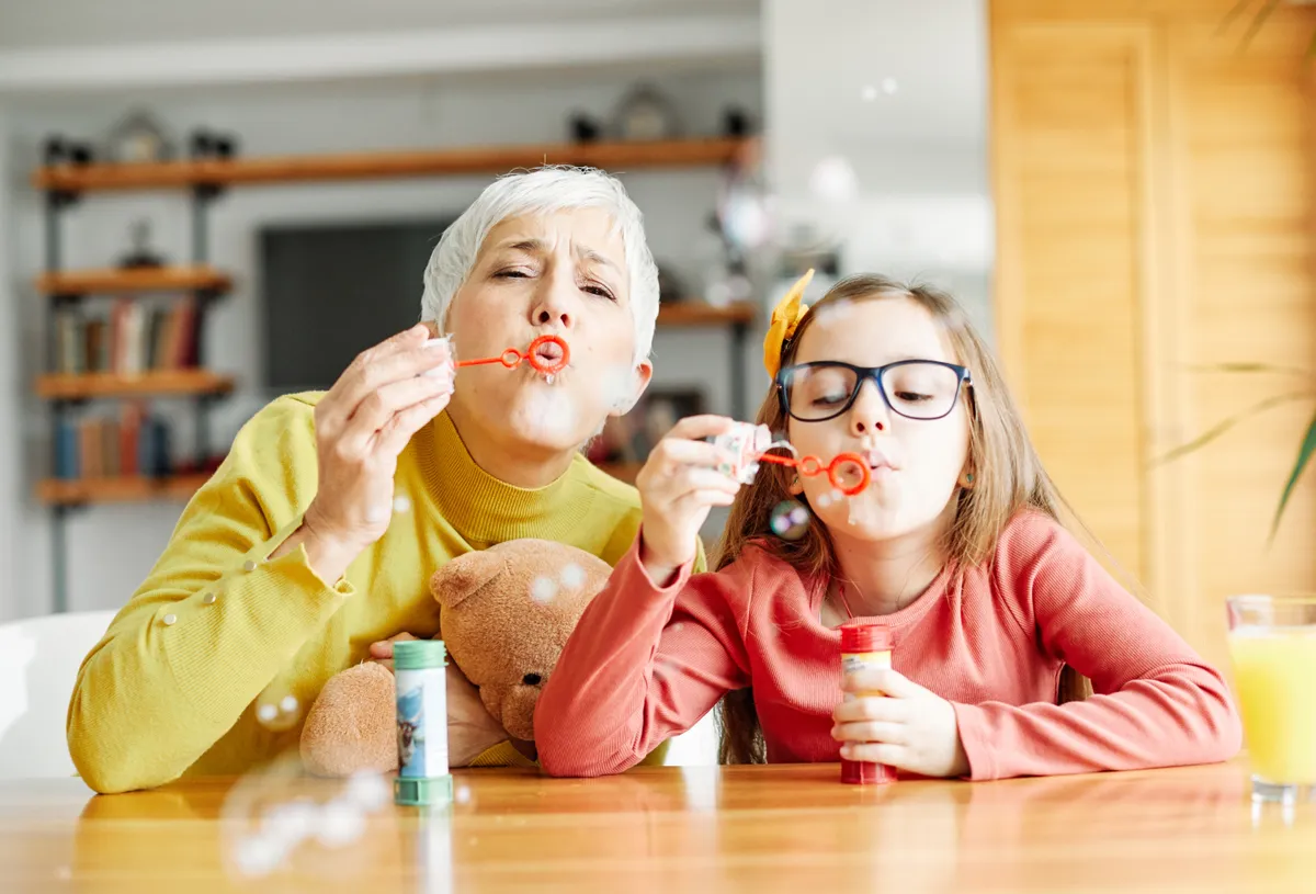 Remek nagyszülő-unoka kapcsolattal rendelkező nagymama és unokája buborékfújózik.