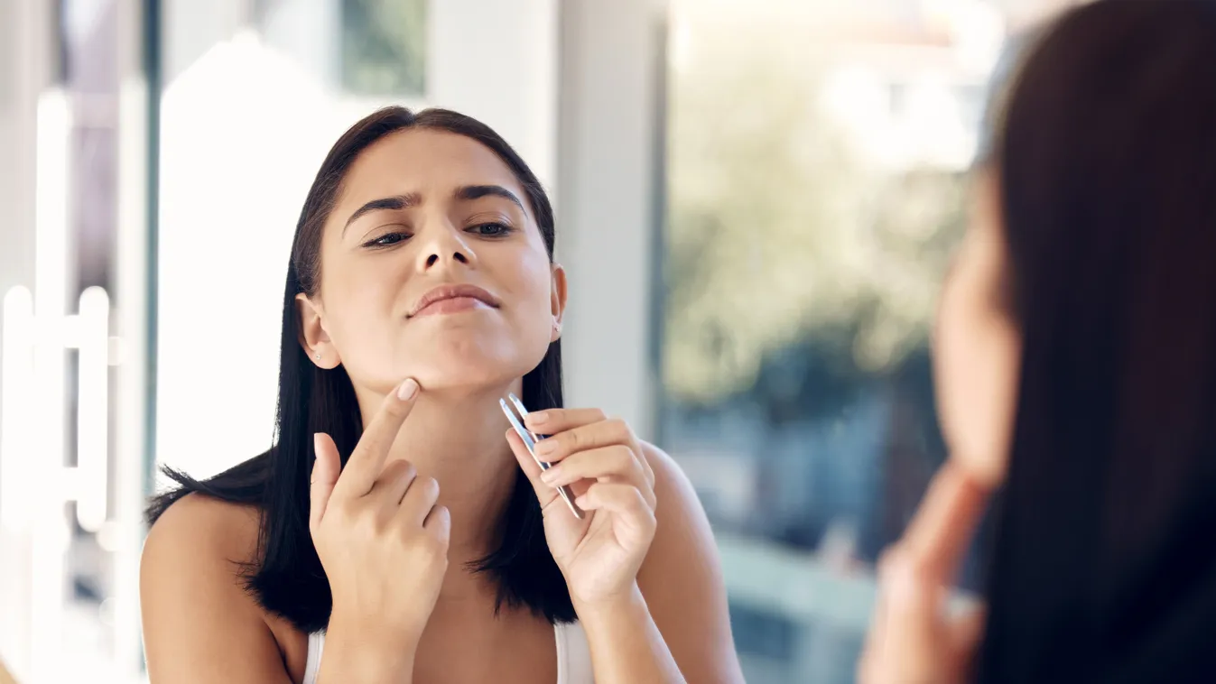 Erős női arcszőrzetű lány csipeszeli az állát.