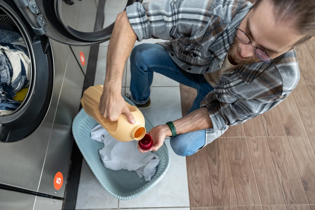 Férfi adagolja a legjobb mosószert a mosáshoz.