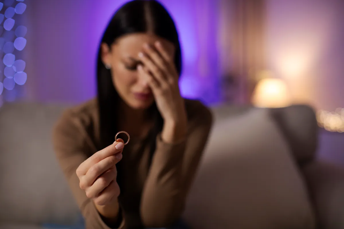 Fiatal nő szomorúan tart egy jeggyűrűt, mert a horoszkóp szerint hiába várja. 