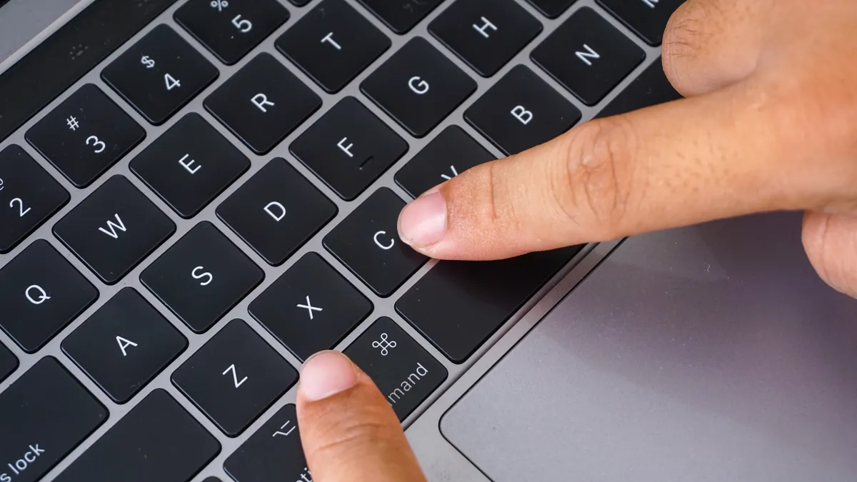 Billentyűkombinációkat használó ujjak egy laptop billentyűzetén.