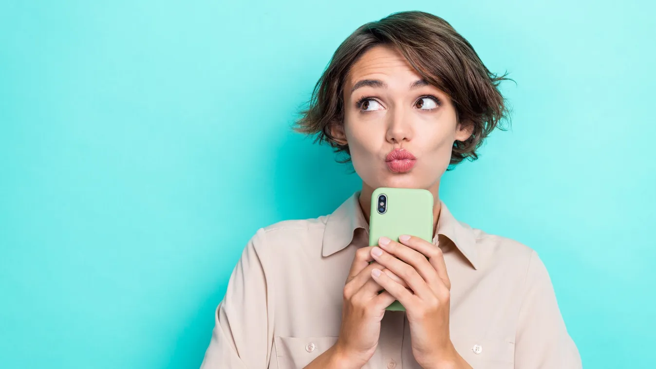 Telefonfüggőségben szenvedő fiatal nő az okostelefonjával a kezében