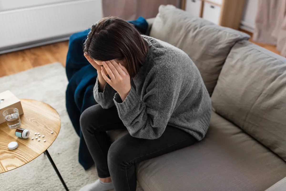 Nyugtatókon élő nő éppen stresszel, a kanapén ülve.