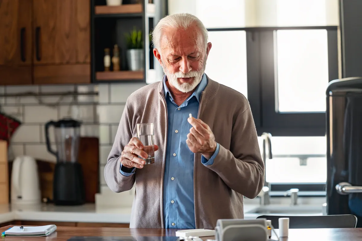 Idős férfi vitamint vesz be, hogy elkerülje a vitaminhiányt. 