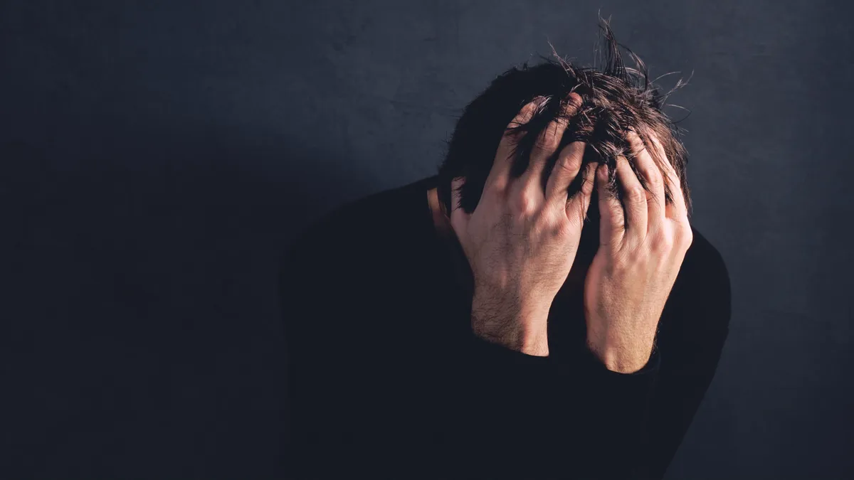 Tanult tehetetlenségben szenvedő férfi az arcát a kezébe temetve