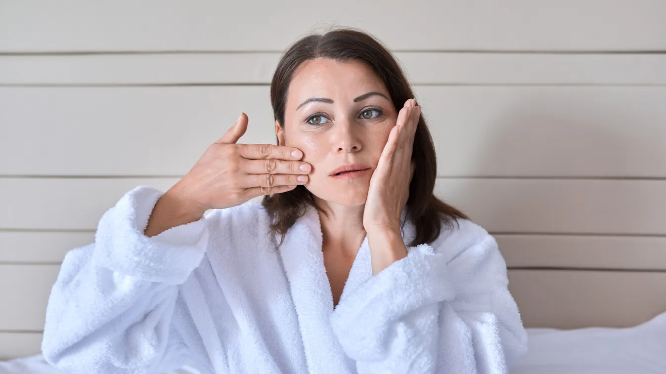 Középkorú nő otthoni arcmasszázst csibál.