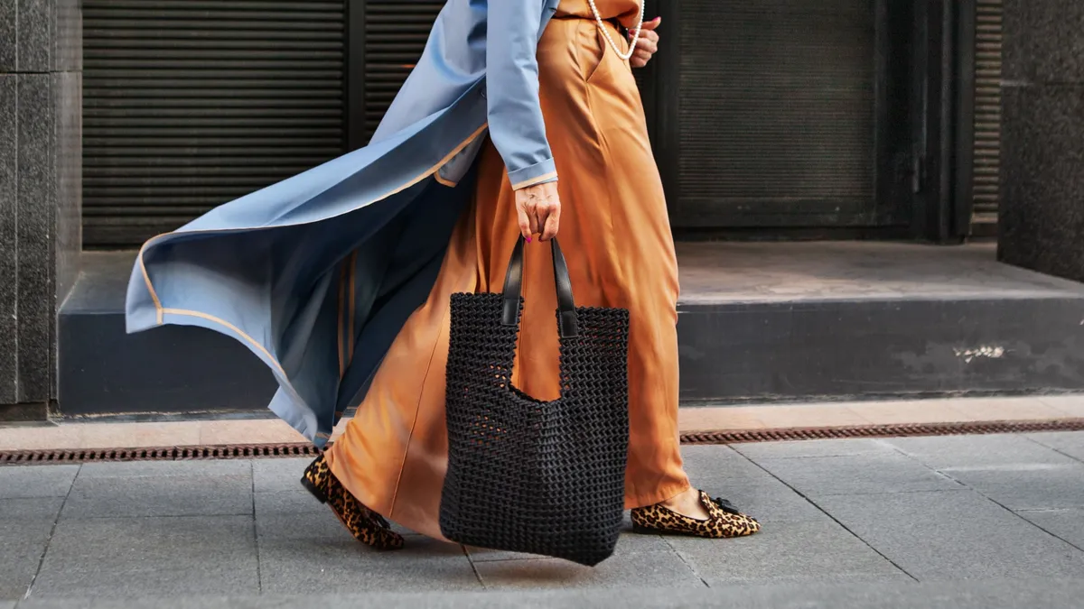 Táskák tavaszra: 50 feletti nő nagy modellel a kezében.