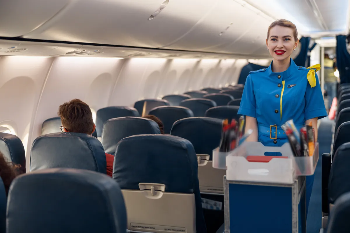 Étkezőkocsit toló stewardess egy repülőúton
