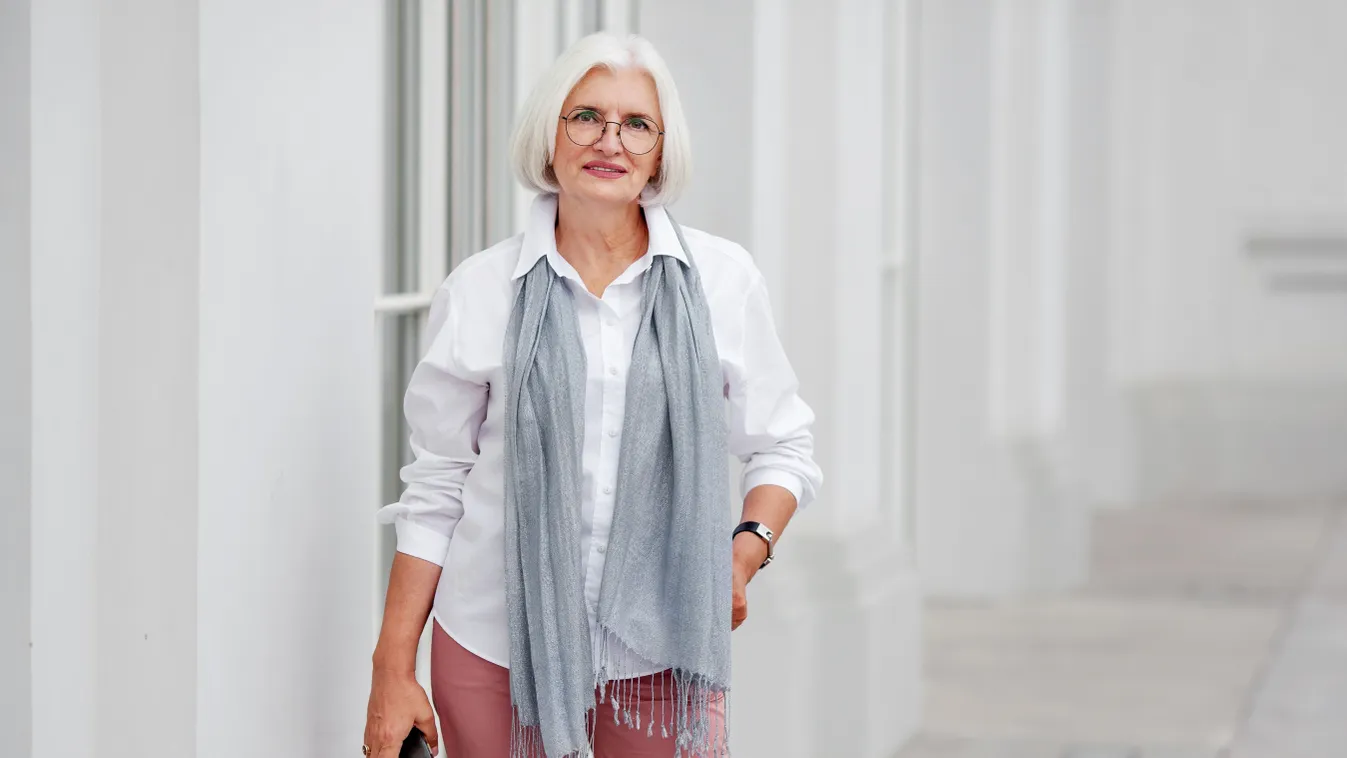 Középkorú nő ősz hajjal, stílusos szettben.