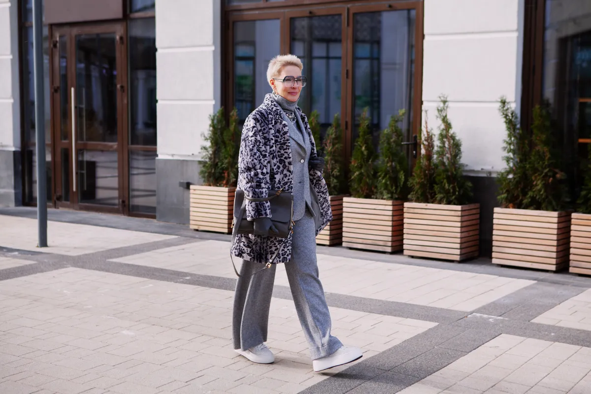 Állatmintás ruhákban sétáló divatós érett nő az utcán.