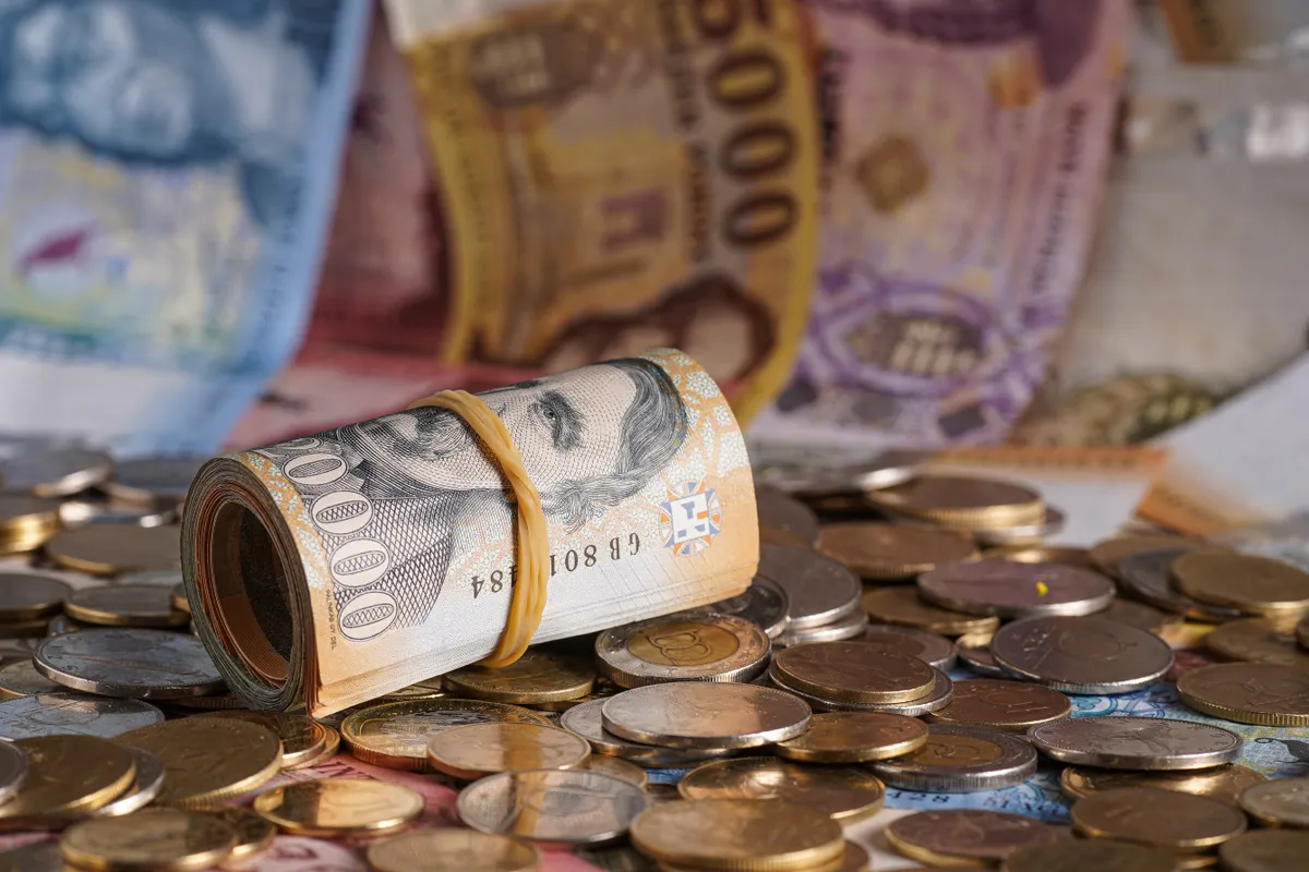 Személyiségtesztben szereplő kép feltekert bankjegyekről és egy halom aprópénzről