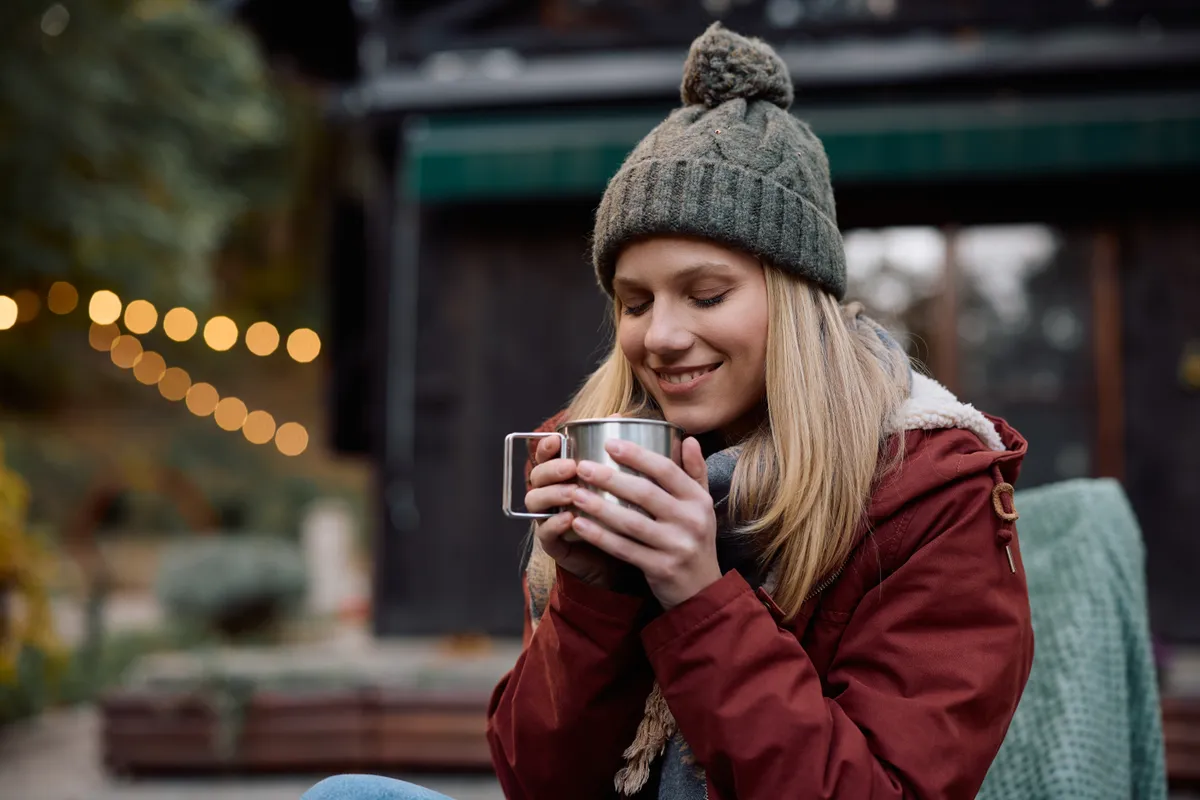 Fiatal nő a szabadban teázik.