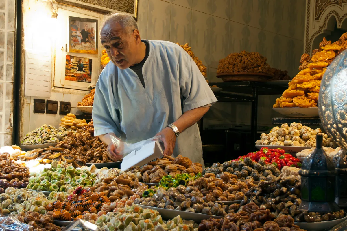 Marokkói édesség árus, miközben a vevővel diskurál.