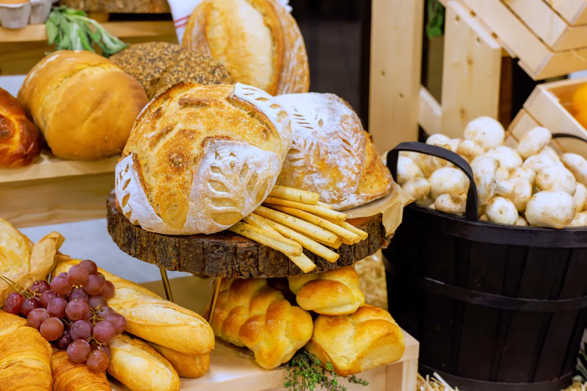 Olcsó kenyérfélék az asztalon - fehér és kovászos kenyerek, kalácsok és bagettek.