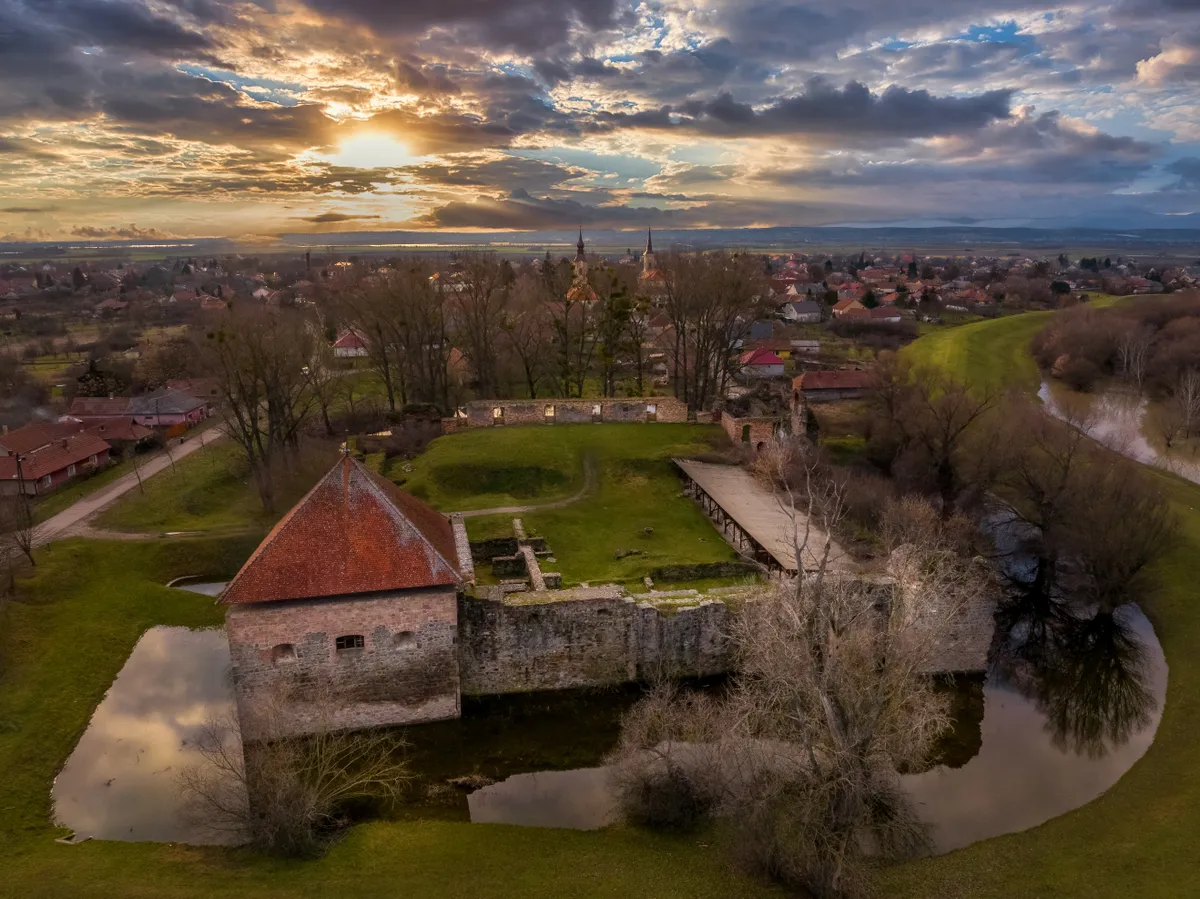 Az ónodi vár, háttérben a településsel napnyugta idején.