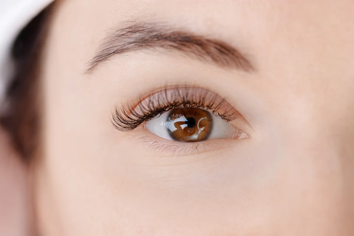 Szempillanövesztő szérumot akalmazó, hosszú szempillájú, barna szemű nő