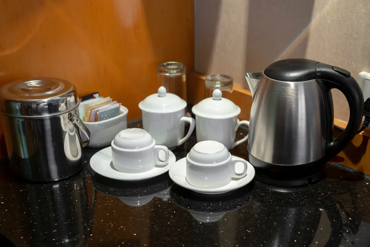 Hotelszoba vízforralóval, teáskészlettel, poharakal.